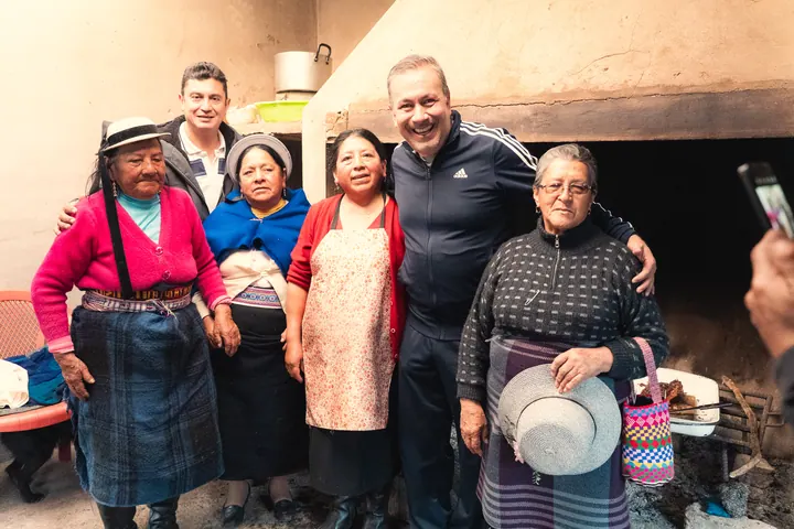 Doryan Jara posa con cuatro mujeres de la parroquia San Juan frente a un horno de leña donde se asa carne.